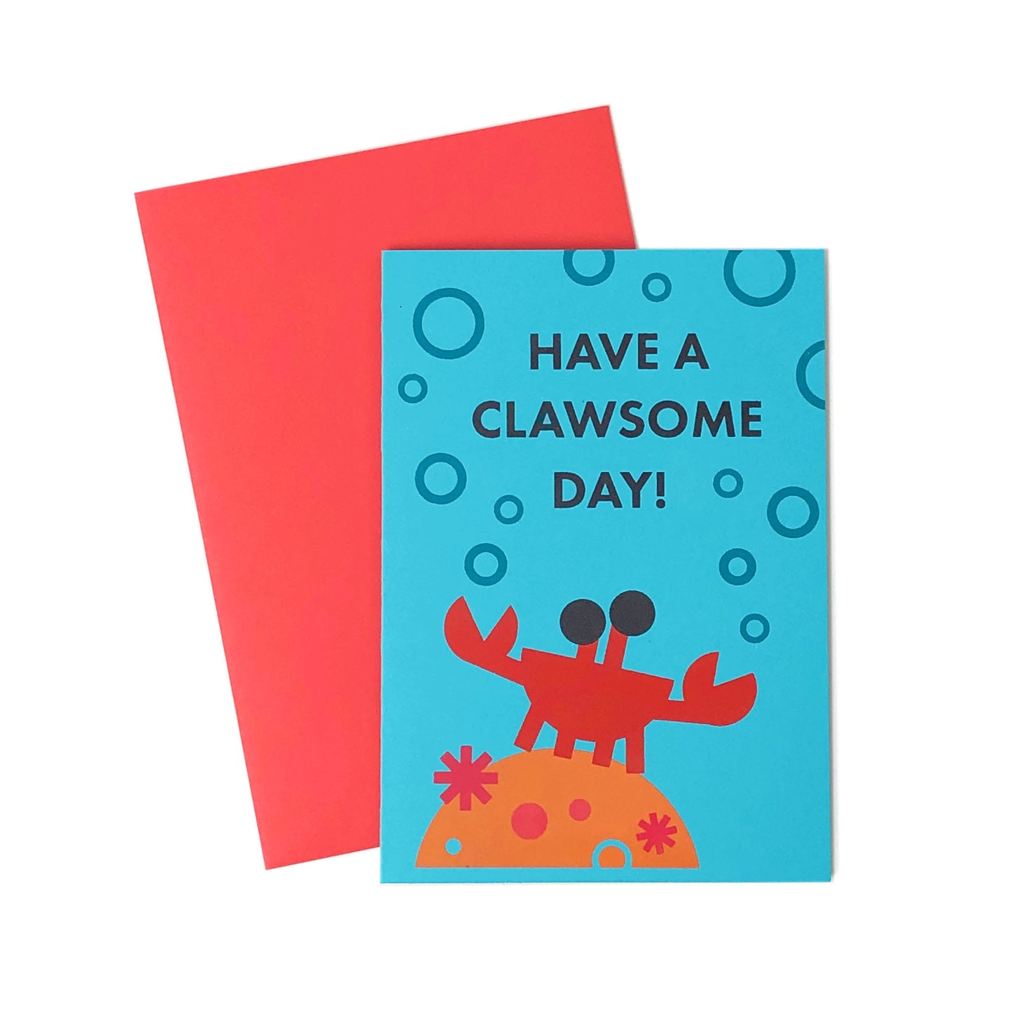 Blue greeting card with graphic art of a crab on coral, bubbles, and text Have a clawsome day! with an envelope next to it.