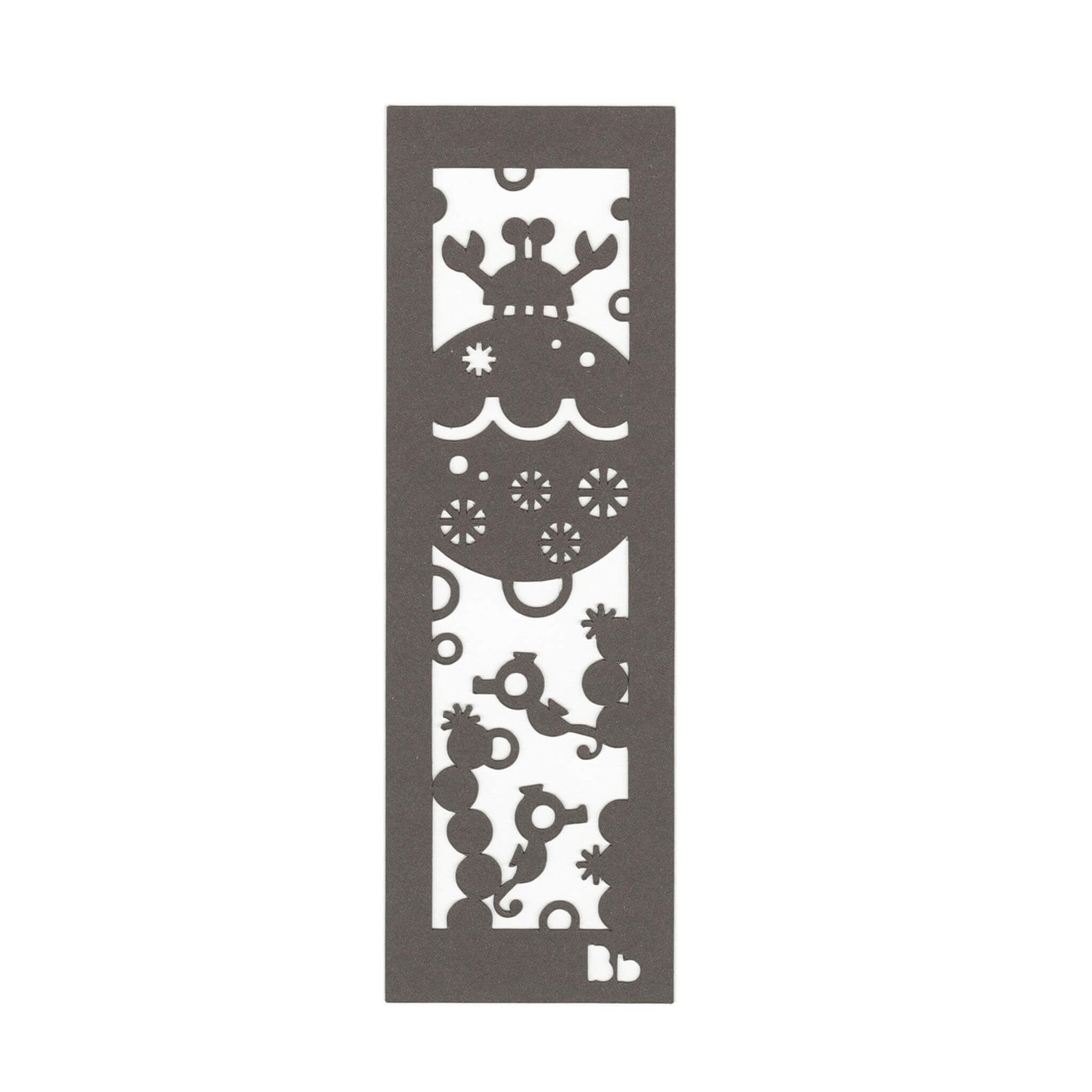 A dark brown paper bookmark with cut-outs of a crab, seahorses, coral and bubbles on a white background.
