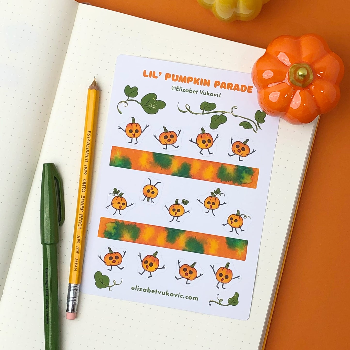 Small pumpkins and washi tape stickers beside pens.