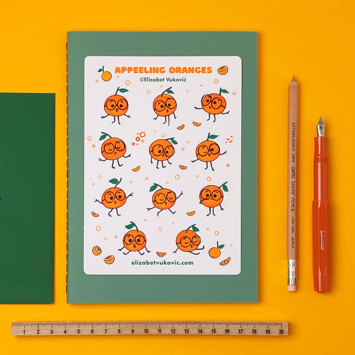 Citrus Oranges stickers beside notebooks and pens.