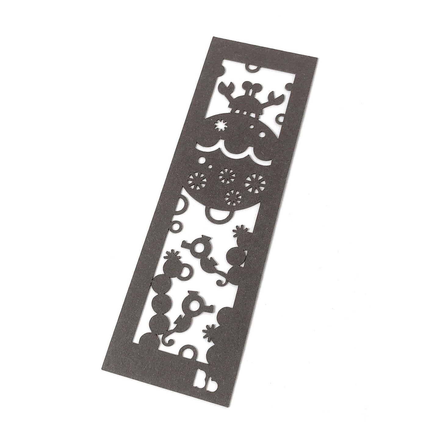 A dark brown paper bookmark with cut-outs of a crab, two seahorses, coral, bubbles and Bb on a white background.