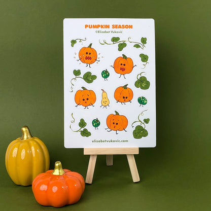 Pumpkin Season Sticker Sheet  featuring illustrated pumpkins and leaves placed on a small easel beside it sit two ceramic pumpkins.