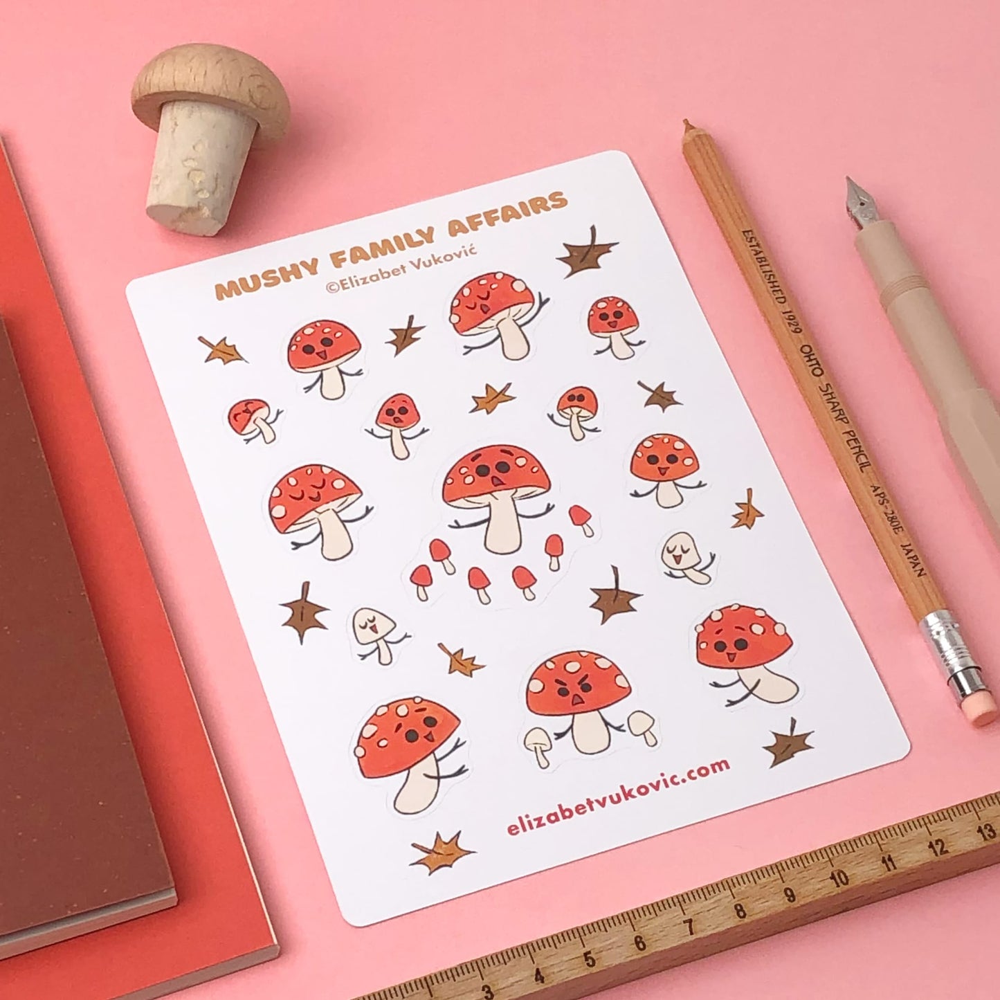 Forest mushroom themed sticker sheet beside pens and notebooks.