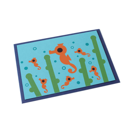 A tilted blue greeting card with one large and five small seahorses, sea weed and bubbles illustrated. Behind the card there's a dark-blue envelope.
