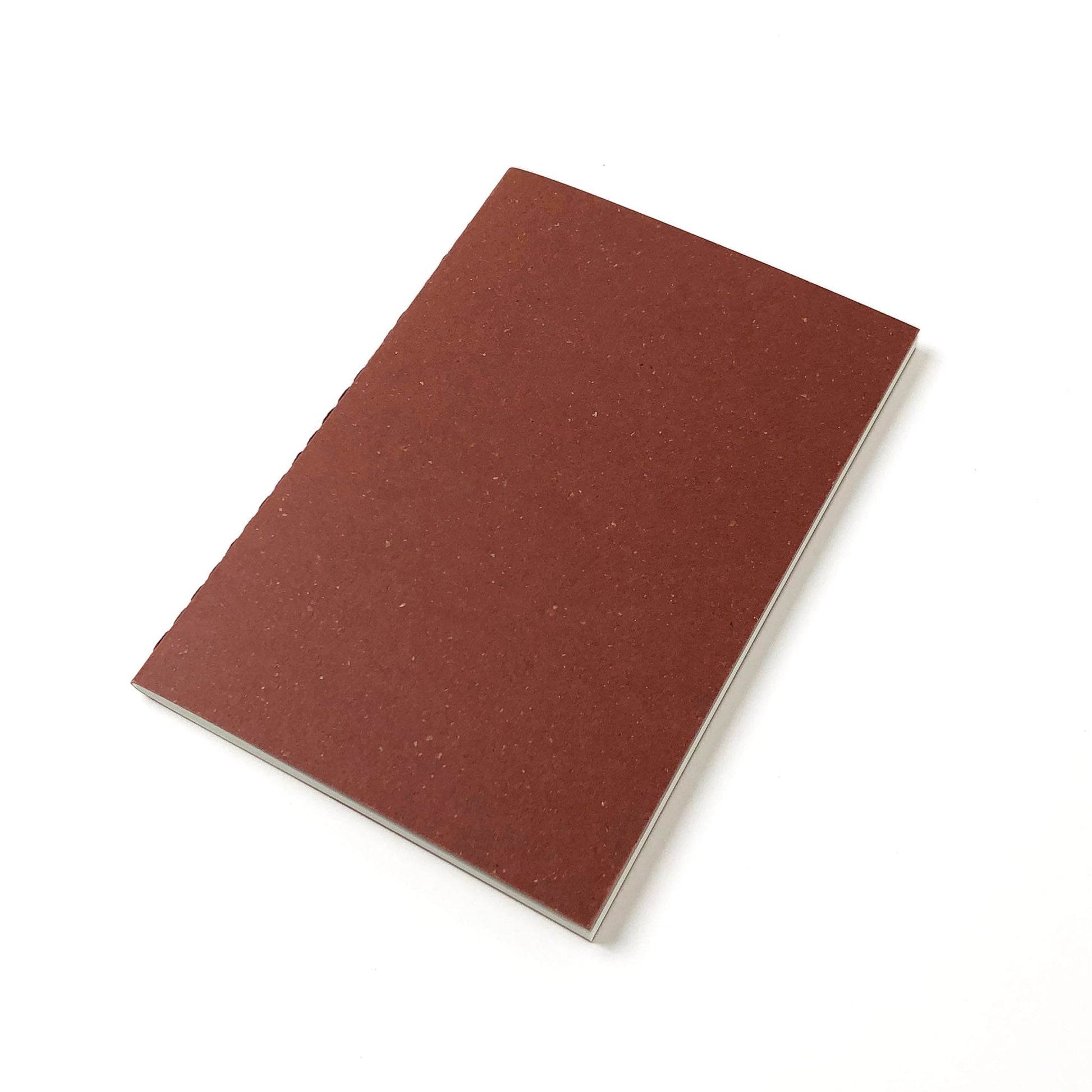 A red-brown speckled notebook with a stitched spine and white pages inside lays on a white background.