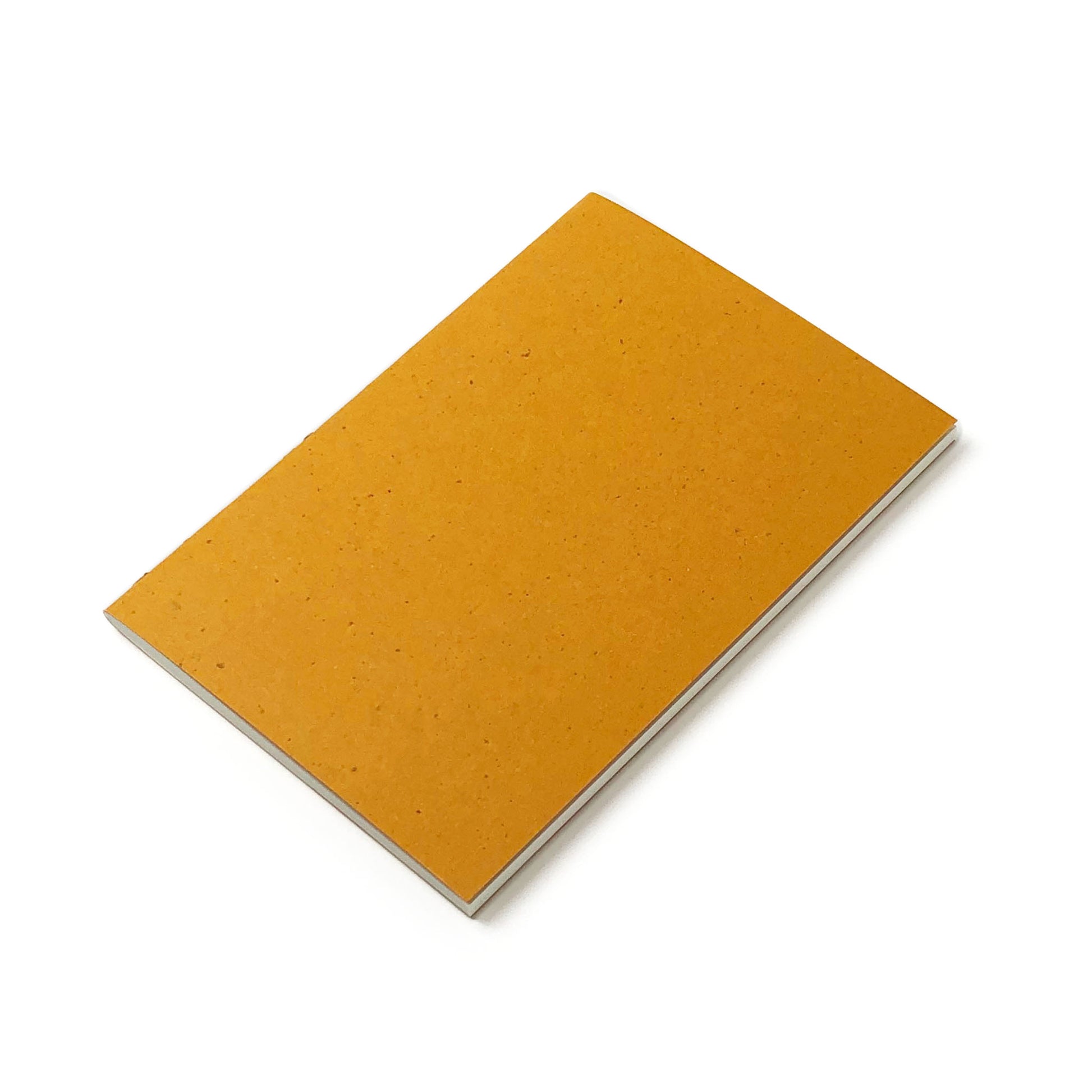 Tilted yellow ochre notebook containing white pages, is positioned on a white background.