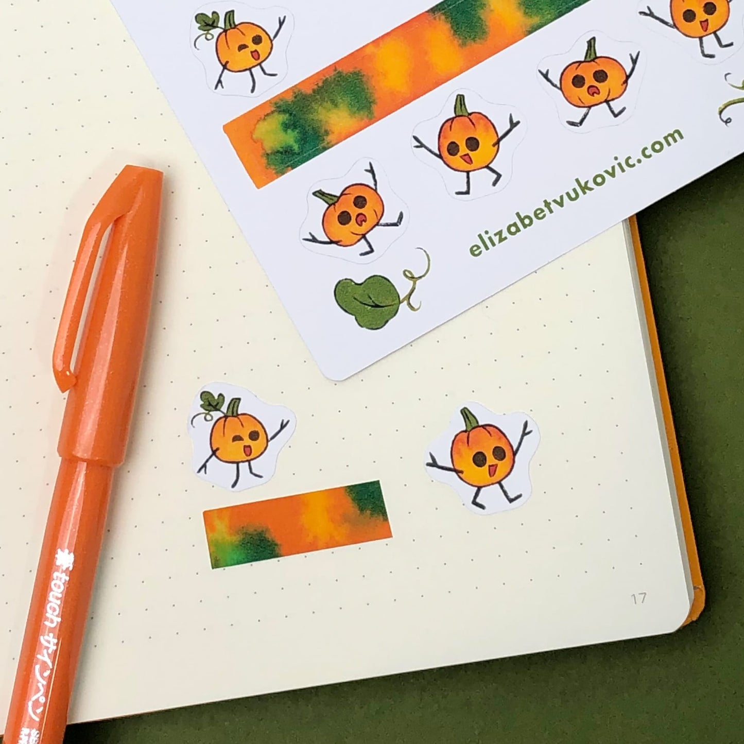 Orange pumpkin stickers and washi tape on a notebook page paired with another pumpkins sticker sheet and pen.