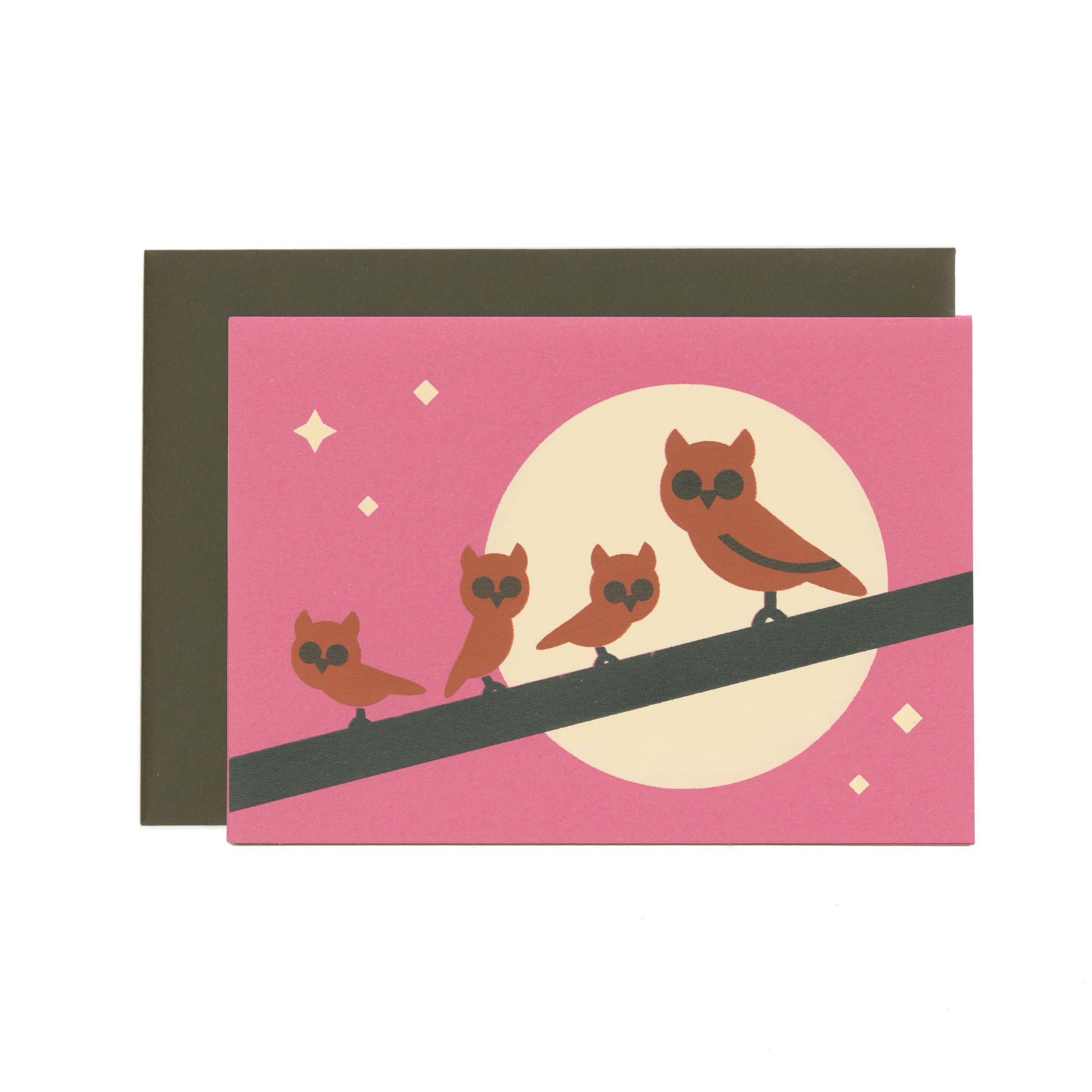 A magenta-purple greeting card with an illustration of one big and three small brown owls on a branch. In the background there is a moon and stars. Behind the card is a dark brown envelope.
