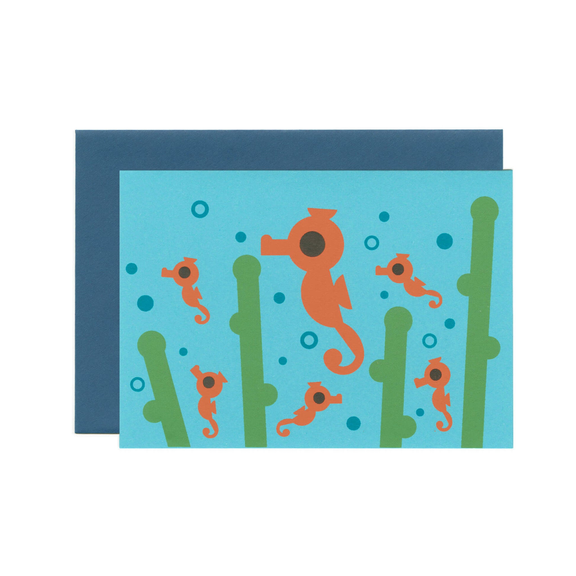 A blue greeting card with an illustration of seahorses, sea weed and bubbles. There's a dark-blue envelope behind the card.