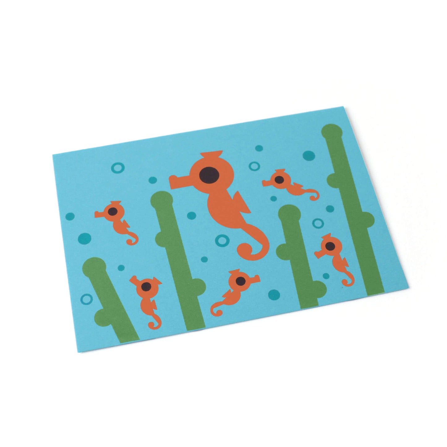 A tilted blue greeting card with seahorses, seagrass and bubbles illustrated.