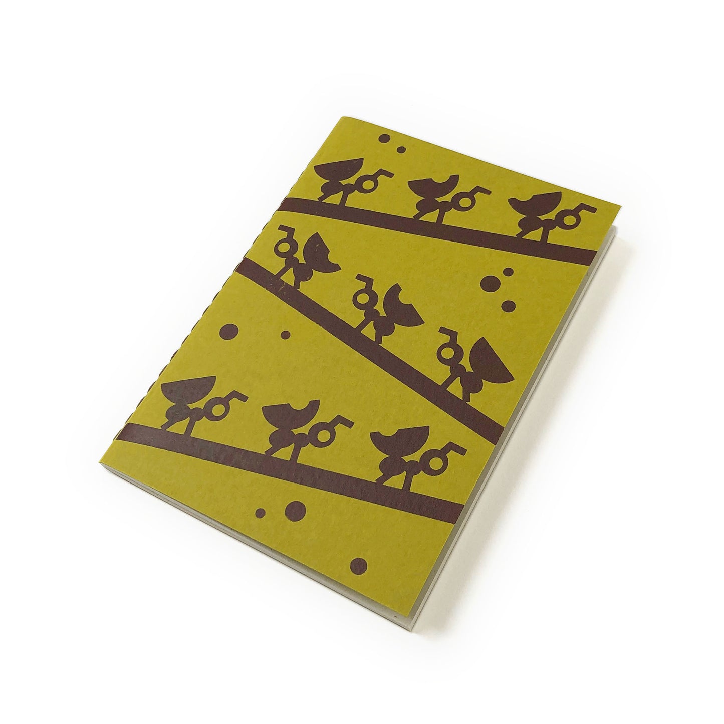 Green notebook with brown illustration of branches with ant rows, and stitched spine on white background.